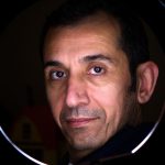 Close-up portrait of a man with a reflective halo effect, front facing and pensive look.